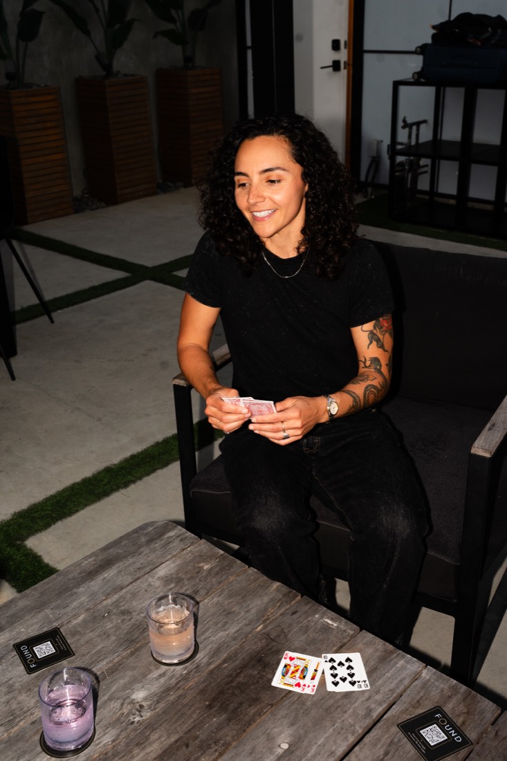 A woman laughing over a card game on a patio
